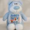 Blå bamse med navn og dato brodert på magen.