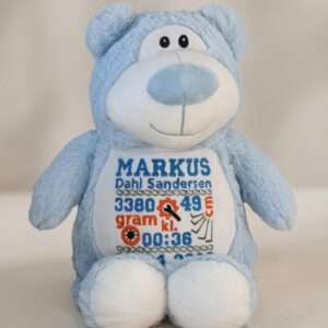 Blå bamse med navn og dato brodert på magen.