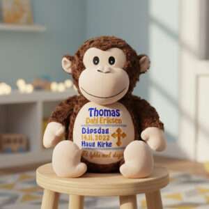 Ape bamse med navn og dato brodert på magen sitter på en krakk i et barnerom.