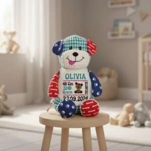 Hund bamse med navn og dato brodert på magen sitter på en krakk i et barnerom.