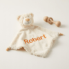Koseklut bamse med brodert navn og vinger på ryggen.