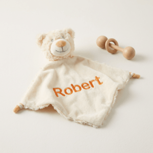 Koseklut bamse med brodert navn og vinger på ryggen.